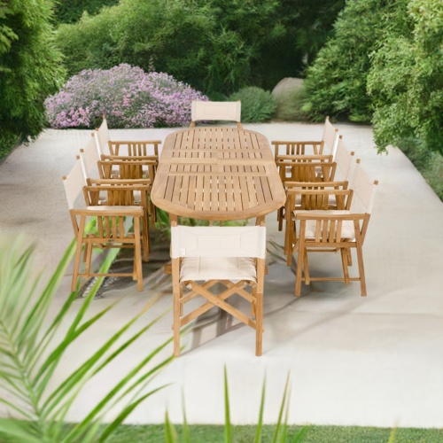 70015 Montserrat Director 9 piece teak Dining Set end angled view on concrete patio surrounded by landscaping plants and trees in the background