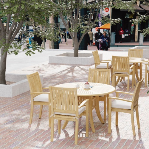 70027 Grand Hyatt 5 pc Dining Set on brick patio showing 2 with table settings with optional seat cushions outdoors with landscape trees and people and store fronts in background