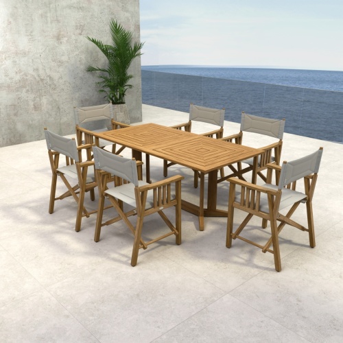 70360 Pyramid Director 7 piece teak Dining Set of 6 teak Director Chairs and Pyramid Teak Dining Table angled aerial view on stone patio with potted palm and ocean in background