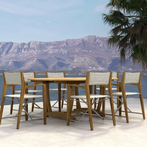 70366 Oval Odyssey Chair 7 pc Dining Set of Martinique Oval Table and 6 Odyssey Director Chairs on outdoor terrace next to palm tree and ocean and mountain background