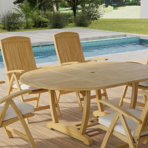 70367 Martinique Barbuda Recliner Dining Set showing partial closeup angled view on patio next to a pool with landscaping trees and privacy fence in the background   