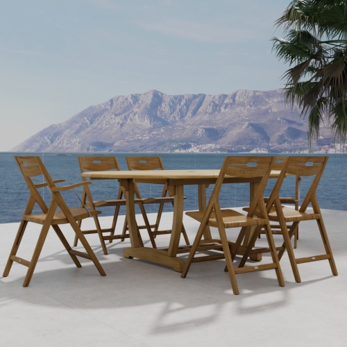 70371 Oval Surf Chair 7pc Dining Set of Martinique Oval Table and 6 Odyssey Director Chairs on outdoor terrace next to palm tree and ocean and mountain background