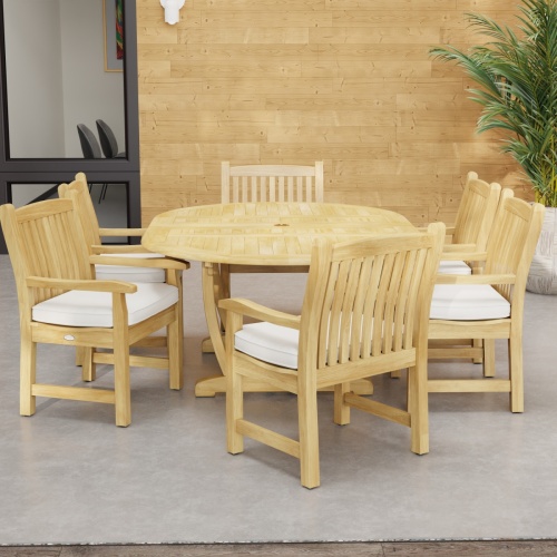 70374 Oval Veranda Chair Dining Set of Martinique Teak Oval Table and 6 Veranda Dining Chairs on outdoor terrace in front of a building with paneled wall and window and potted plant in the background