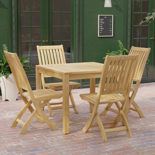 70570 Barbuda 5 pc Dining Set of Barbuda Bistro Teak 36 inch Square Dining Table and 4 Barbuda Folding Chairs side angled view on brick paver patio with door and window of building in background