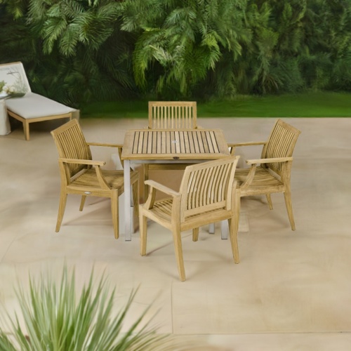 70603 Vogue Laguna 5 pc Dining Set of Vogue Teak 36 inch Square Table and 4 Laguna Dining Arm Chairs angled aerial view on patio with plants and white chaise in the background 