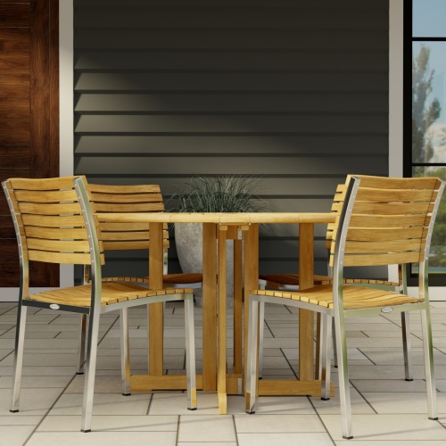 70735 Barbuda Vogue 5 pc Teak DIning Set of Barbuda 48 inch Round Dining Table and 4 Vogue Teak and 304 Stainless Steel Side Chairs on tiled patio with house in the background