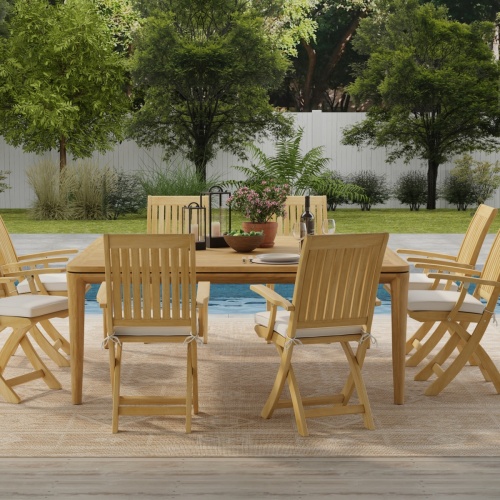 70813 Veranda Barbuda Dining Set of Veranda Square Dining Table and 8 Barbuda Folding Arm Chairs side view on deck in front of pool with fence and landscaping plants in background