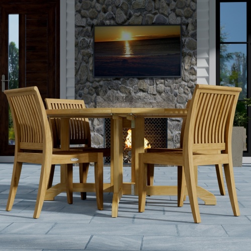 70851 Barbuda Laguna 5 pc Dining Set of Barbuda Folding Teak Table and 4 Laguna Side Chairs corner view on stone patio with 2 doors and a television above a fireplace in the background