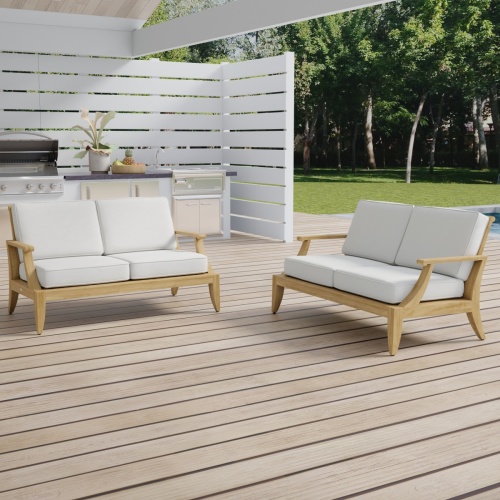 70914 Laguna Loveseat Set of two laguna teak loveseats with cushions on outdoor patio with outdoor kitchen and privacy wall and plants in background 