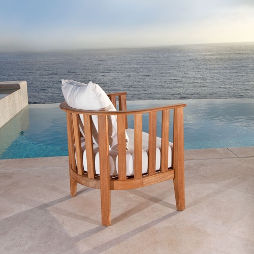 12170DP Kafelonia teak Barrel Chair with cushions back angle outside on concrete patio overlooking pool and ocean in background