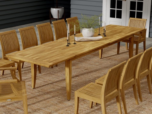 15978  laguna teak extension table with 6 candlestick holders and potted plant with 10 side chairs angled side view on patio with house in background