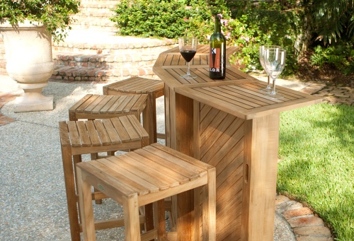  17112 Somerset teak bar and stools bar fully opened showing three wine glasses and wine bottle on bar top displayed on patio with potted plants stone steps vegetation in background 