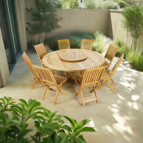 70018 Buckingham Barbuda 9 pc Dining Set angled with optional Lazy Susan in the center on a stone patio surrounded by plants next to glass doors and a privacy wall and trees in the background 