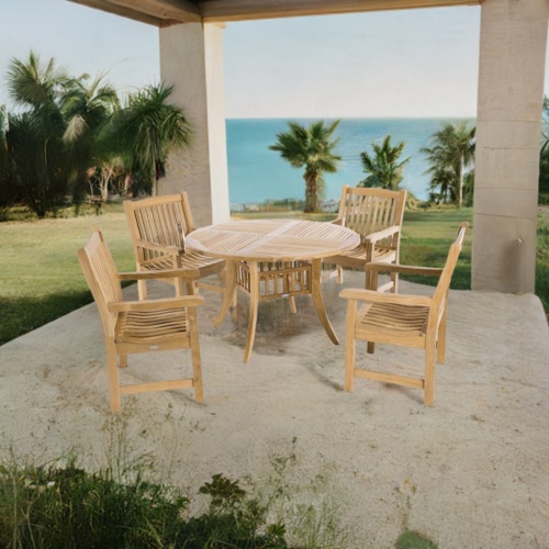 70159 Hyatt Veranda 5 piece teak Dining Set of 4 armchairs and round 48 inch diameter table angled aerial view on stone patio surrounded by plants and an ocean background