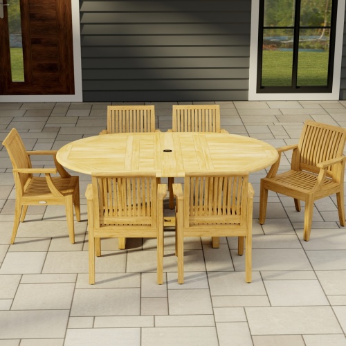 70306 Martinique 7 pc Teak Dining Set of Martinique Teak Oval Extending Dining Table and 6 Laguna DIning Chairs side view on stone patio with a house window and door in the background