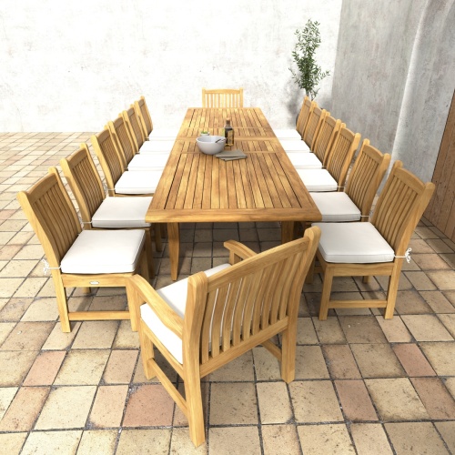 70361 Grand Laguna 15 piece teak Dining Set of 12 teak dining chairs around teak rectangular dining table around teak rectangular extendable dining table angled end view on paver patio and potted tree in background 