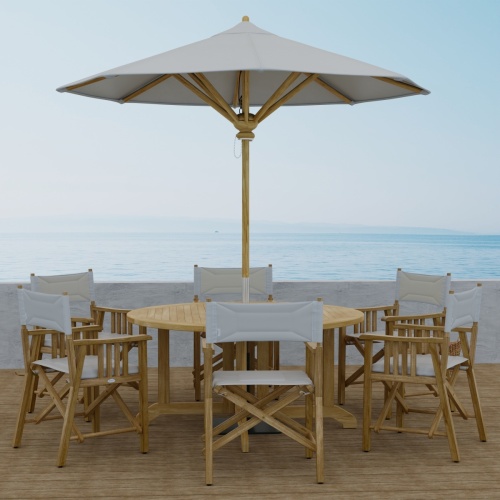 70362 Barbuda Director 7 piece Teak Dining Set of 6 Director Chairs and Round 60 inch diameter folding teak dining table with optional opened umbrella side view with ocean background  