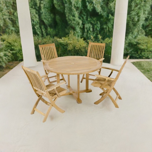 70536 Barbuda 5 piece Dining Set of Barbuda Teak 48 inch round dining table and 4 Barbuda folding armchairs aerial angled view on a patio with 2 pillars and landscaping plants in the background