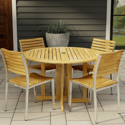 70735 Barbuda Vogue 5 pc Teak DIning Set of Barbuda 48 inch Round Dining Table and 4 Vogue Teak and 304 Stainless Steel Side Chairs on tiled patio with potted plant and house in the background