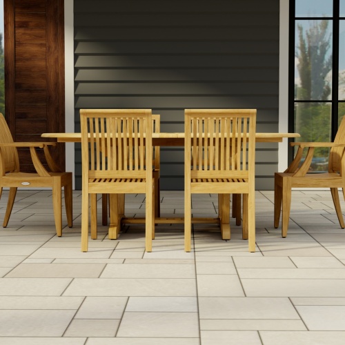 70363 Martinique Laguna 7 pc Dining Set of Martinique Teak Oval Table and 2 Laguna Dining Armchairs and 4 Laguna Side Chairs side view on tile patio with a door and window of house in background