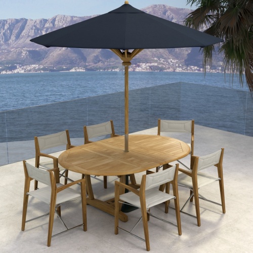 70366 Oval Odyssey Chair 7 pc Dining Set angled aerial view with opened optional black umbrella on outdoor terrace next to palm tree with the ocean and mountain background 