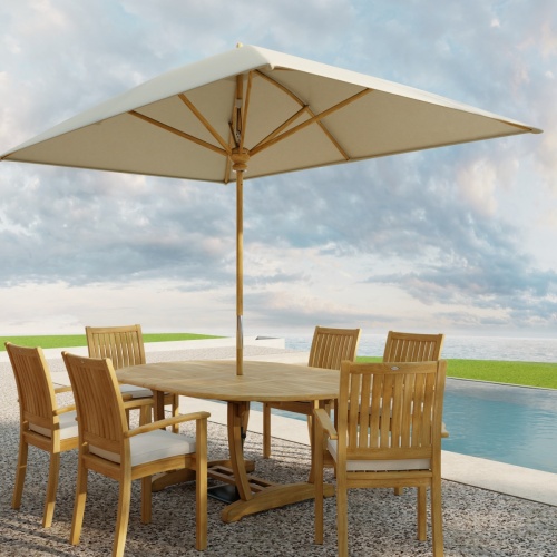 70372 Oval Sussex Chair 7 pc Dining Set of Martinique Teak Oval Table with optional Rectangular Umbrella and 6 Sussex Dining Chairs on outdoor terrace next to a pool with the ocean in the background 