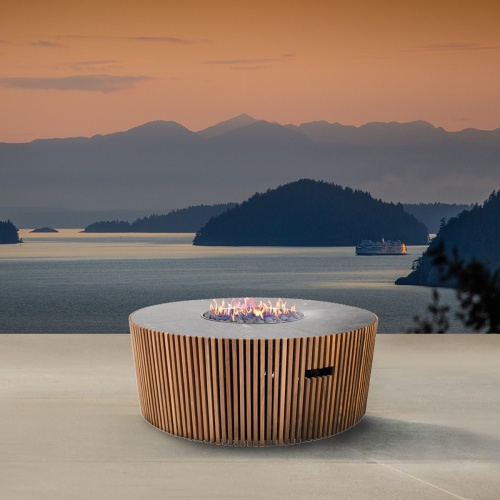 14100 Agora Round Fire Table angled view with lake in background and boat going by with sunset bacground