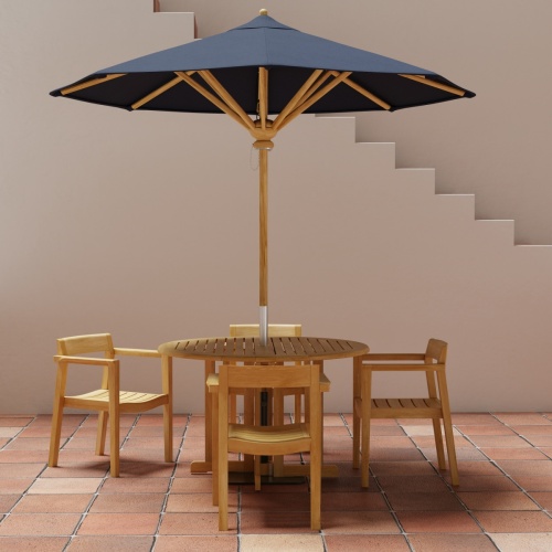 70384 Barbuda Horizon teak round folding dining table and 4 Horizon Dining Armchairs with optional umbrella in table center in side view on stone patio with staircase in background