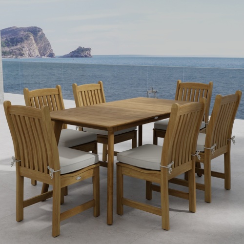 70385 Veranda Surf 7pc Dining Set of Surf Rectangular Dining Table and 6 Veranda Side Chairs with optional seat cushions angled corner view on stone patio with the ocean in background