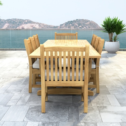 70792 Veranda 9 pc Teak Dining Set with optional seat cushions end view showing a potted plant and ocean view in background 