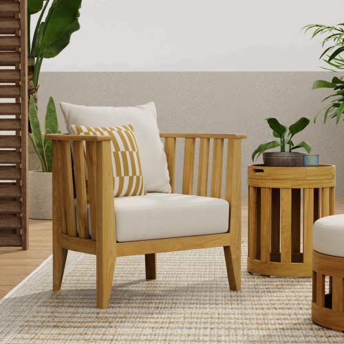 12170DP Kafelonia teak Barrel Chair with side table and partial view of ottoman with potted plants and privacy wall in the background