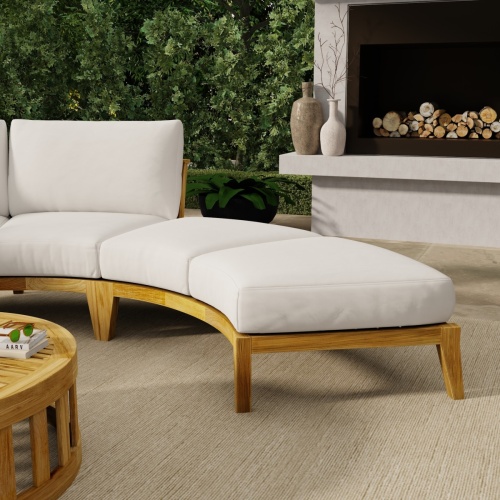 13342DP Kafelonia Backless Curved Sofa Sectional with optional cushion in canvas color on patio with fireplace and landscaping plants in background 