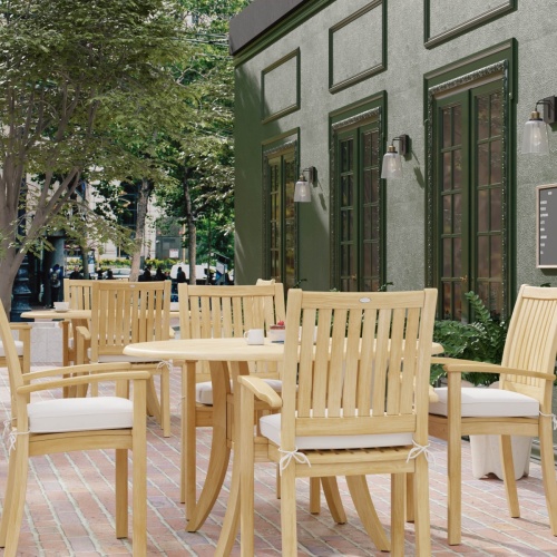 70027 Grand Hyatt 5 pc Dining Set on brick patio showing 2 with table settings with optional seat cushions outdoors between landscape trees and store fronts in background