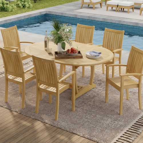 70214 Martinique Sussex Teak 7 pc Dining Set of Martinique Teak Oval Table and 6 Sussex Teak stacking Arm Chairs aerial view next to pool with plants in background