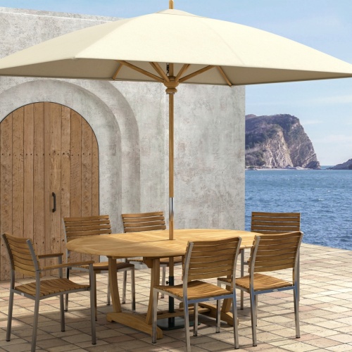 70370 Martinique Veranda 7 pc Oval Dining Set of Martinique Teak Oval Dining Table and 2 Veranda Armchairs and 4 Side Chairs on a patio and wood doors and ocean in background