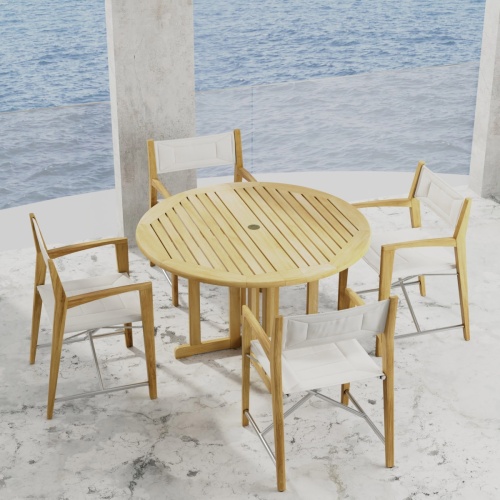 70473 Odyssey Barbuda 5 piece Folding Dining Set of 4 folding director chairs and 48 inch round teak table on marble patio with the ocean in the background 