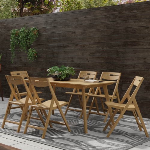 70518 Surf 7 piece teak folding Dining Set with potted plant a book and water glass on large paver patio with privacy wall with hanging plants in background