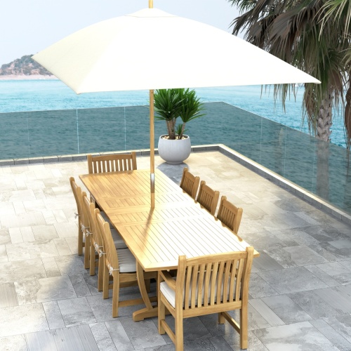 70792 Veranda 9 pc Teak Dining Set with optional seat cushions and umbrella in aerial end view showing a potted plant and ocean view in background 