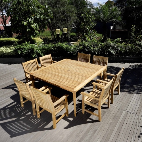 70878 Veranda 9 piece Square teak Dining Set angled view on wood deck with trees and bushes in background