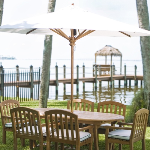 17542 round teak 10 ft market umbrella opened on dining set on grass lawn with bost dock and lake in the background