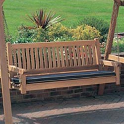 13955bo veranda swinging bench and stand with optional bench cushion on brick patio overlooking grass field with shrubs in background