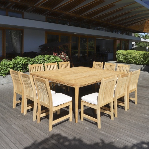 15075 Veranda teak Square Dining Set on wood deck with optional seat cushions and a building and shrubs in background