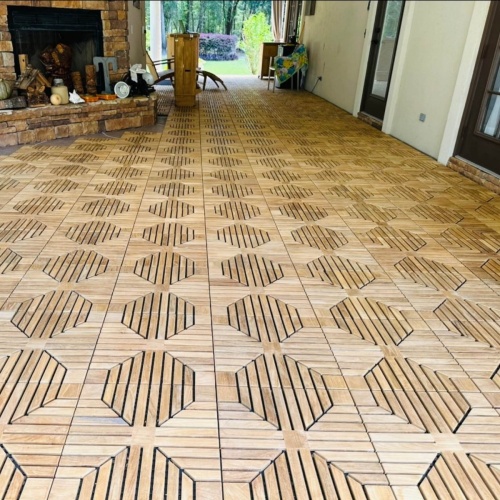 18408P diamond teak tiles assembled together on an outdoor patio with a stone fireplace and trees in background 