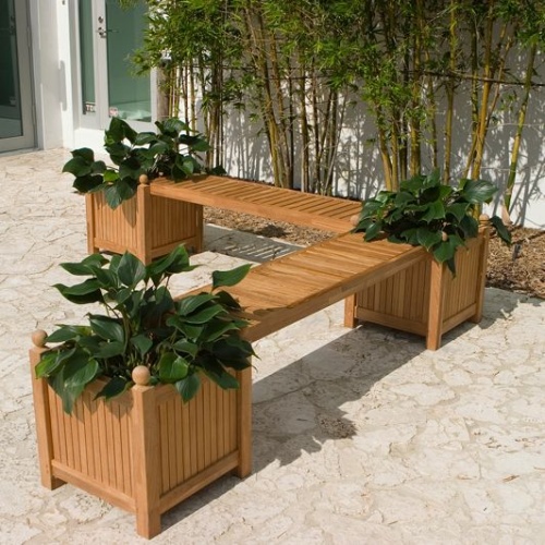 70530 double teak planter bench set with 3 planters with green plants and 2 seat panel on stone patio in angled aerial view next to sliding glass doors with shrubs in background