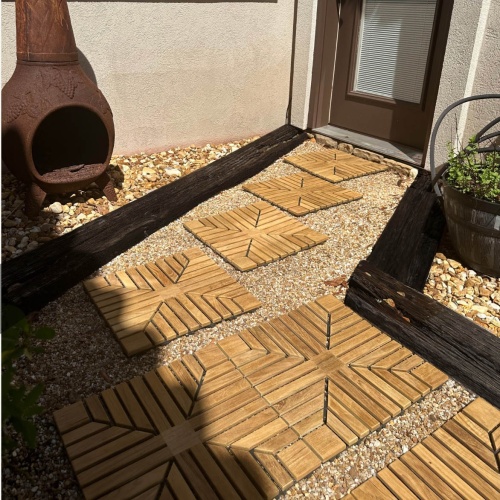 18408P diamond teak tiles showing some connected on a walkway leading to a door with chimenea and landscaping rocks in background