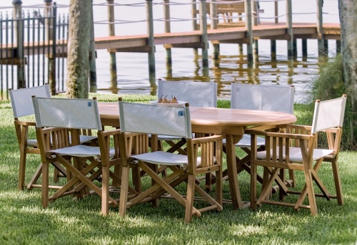 12568f Barbuda teak Directors Chair showing 6 with Montserrat extension table on grass lawn with boat dock and water views in background