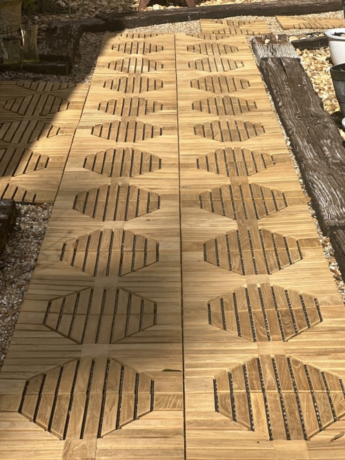 18408P diamond teak tiles assembled together on a walkway in closeup view of design with landscape wood border and rocks on each side