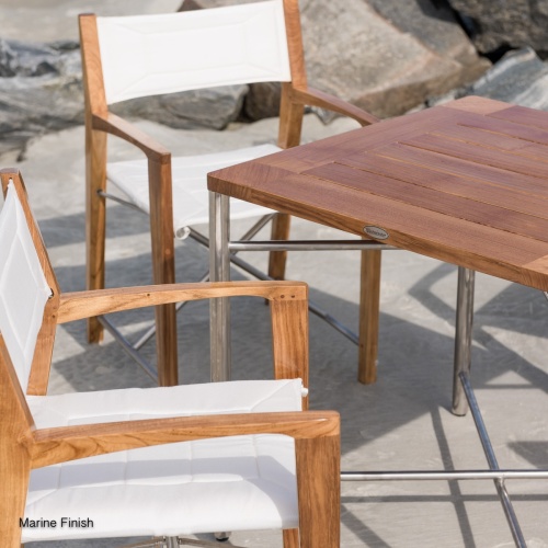 25815 Odyssey Teak and Stainless Steel 32 Inch Square Outdoor Folding Table showing closeup view of table top with Odyssey Chair on boat dock