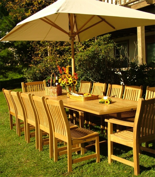 12218 Veranda Chair With Arms with Veranda grand extension table with optional rectangular umbrella in table on grass lawn and landscape plants in background