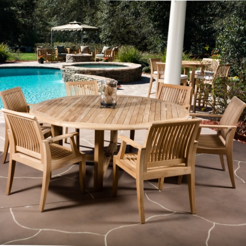 12810 Laguna Dining Armchair showing 6 around a Teak Round Table on patio with pool and landscape plants and trees in the background